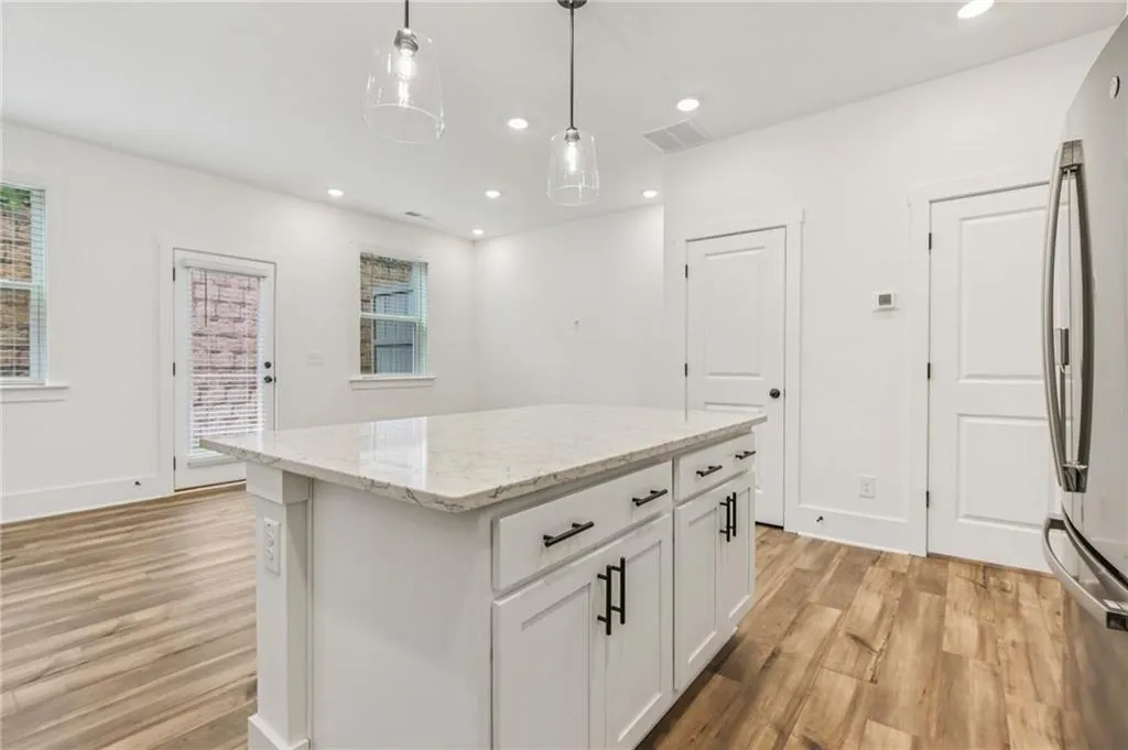 Kitchen with light wood-style floors, freestanding refrigerator, recessed lighting, hanging light fixtures, and white cabinets
