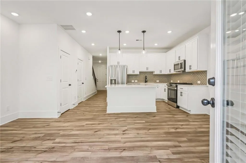 Kitchen featuring stainless steel appliances, light wood-style floors, white cabinetry, light countertops, and recessed lighting
