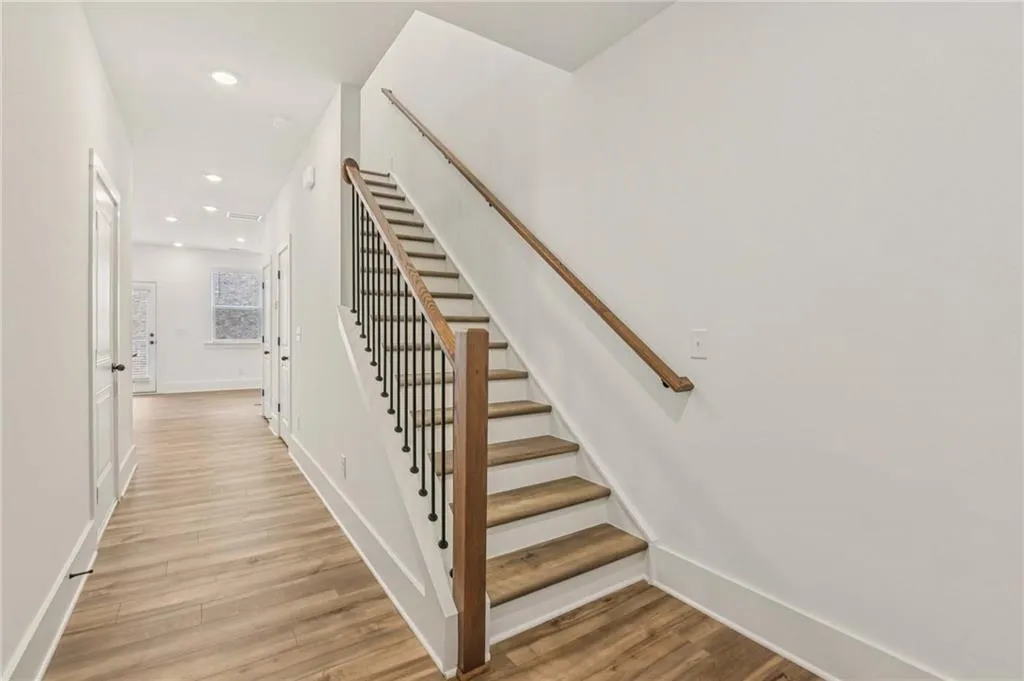 Stairway with wood finished floors and recessed lighting