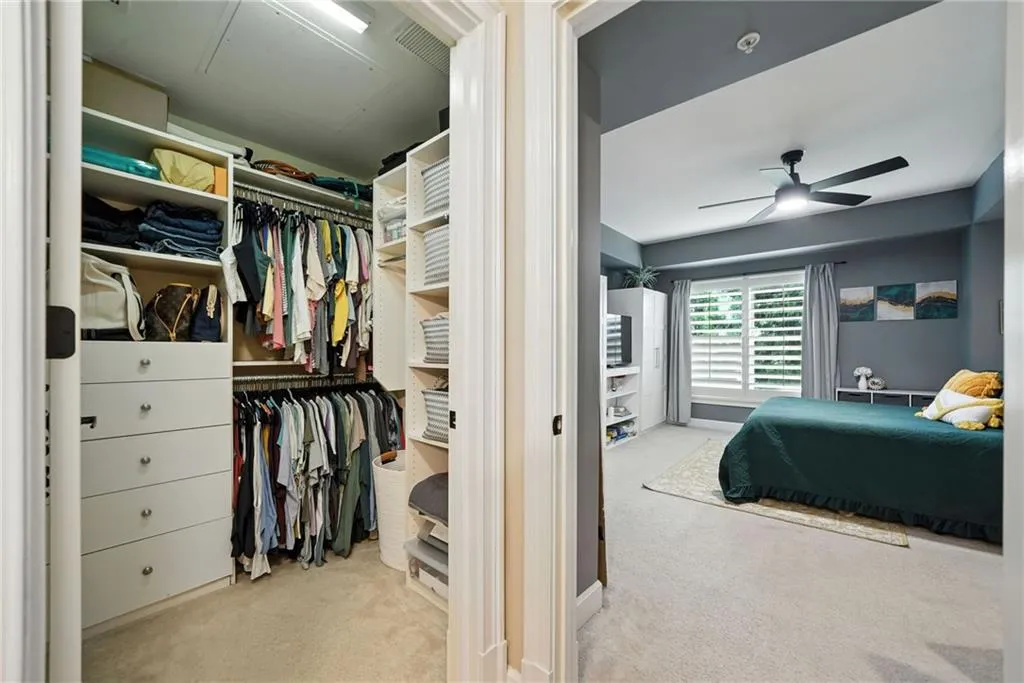 Carpeted bedroom featuring ceiling fan and a closet