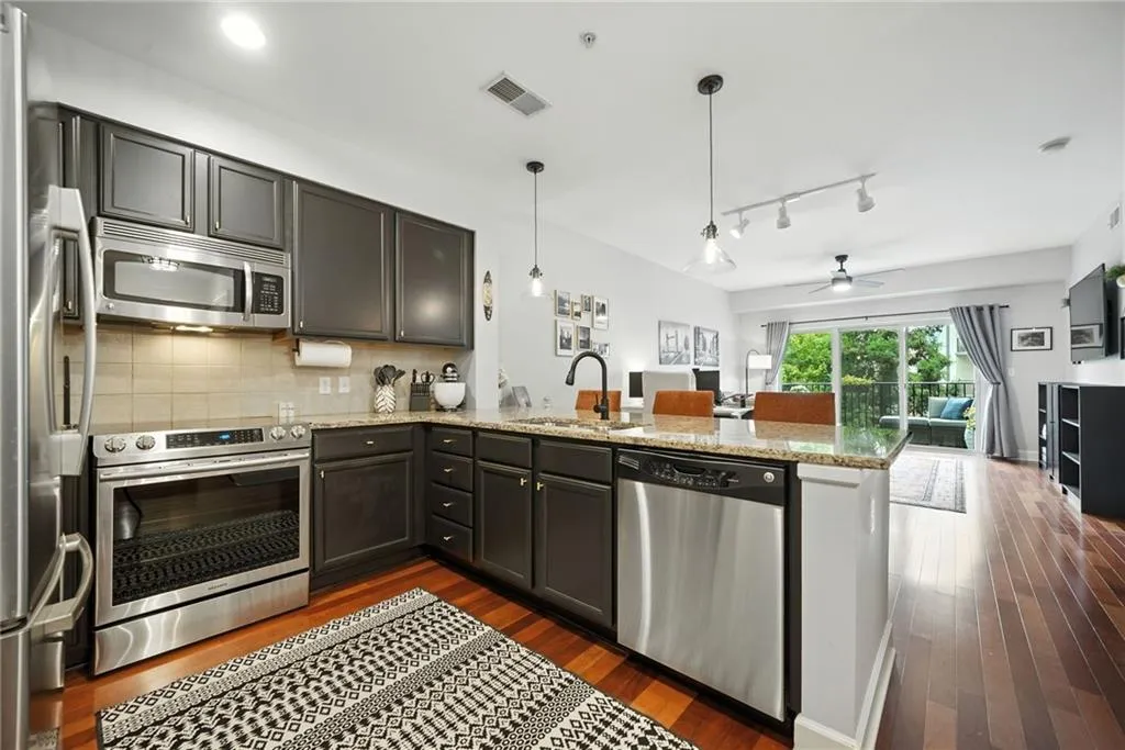 Kitchen with stainless steel appliances, a peninsula, open floor plan, decorative backsplash, and light stone countertops