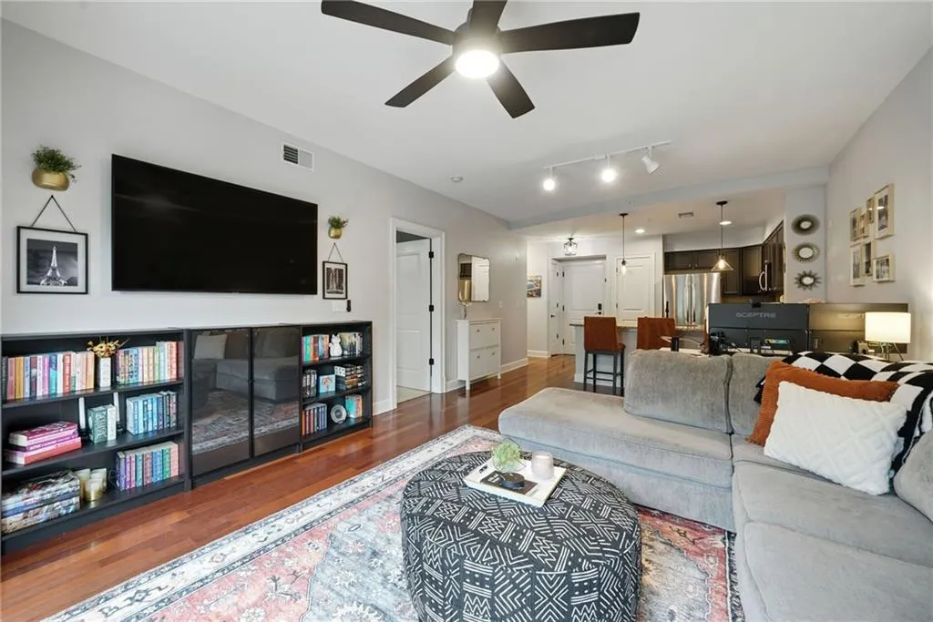 Living room with wood finished floors, ceiling fan, and track lighting