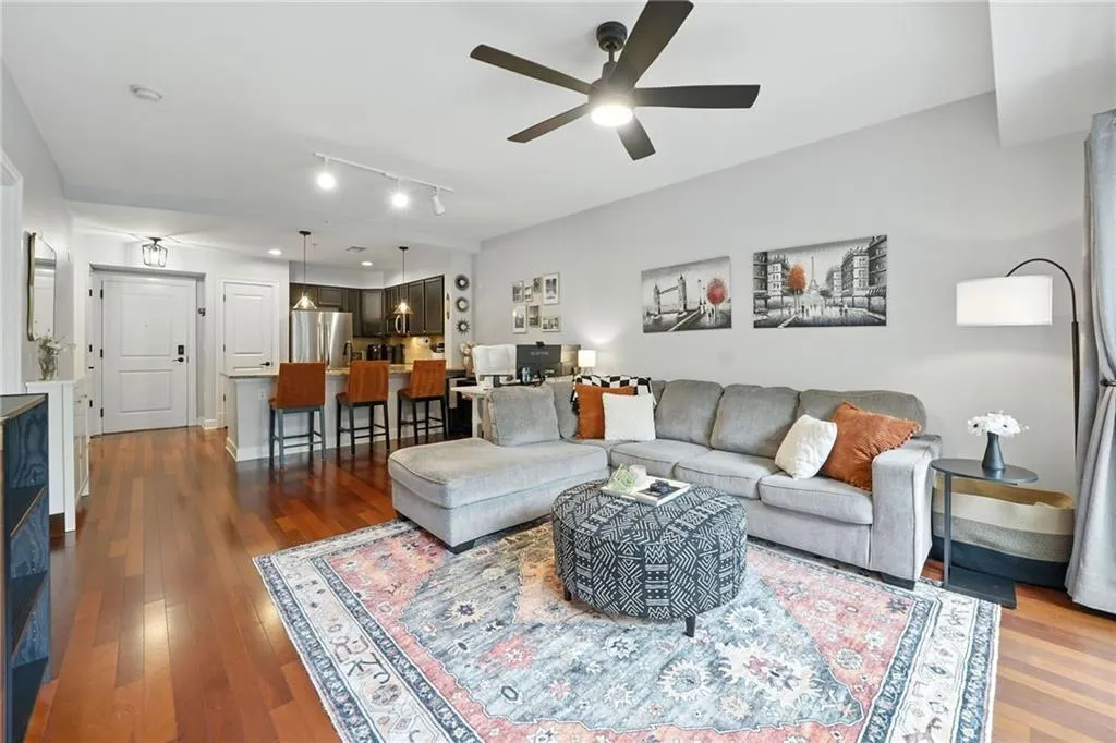 Living room featuring dark wood-style flooring, ceiling fan, and rail lighting
