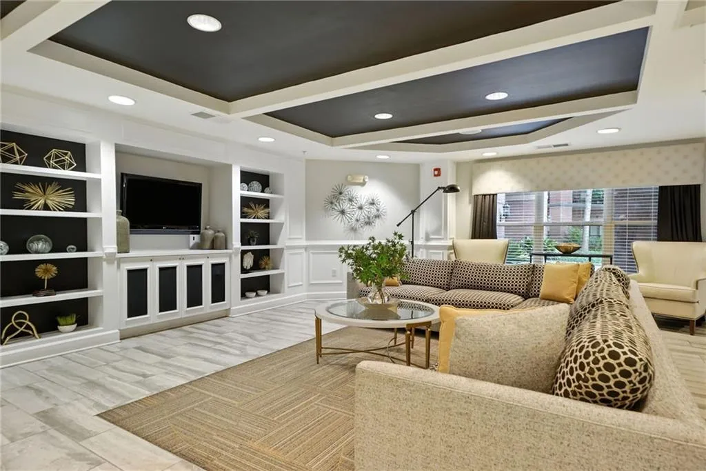 Living area with a tray ceiling, wood finished floors, and recessed lighting