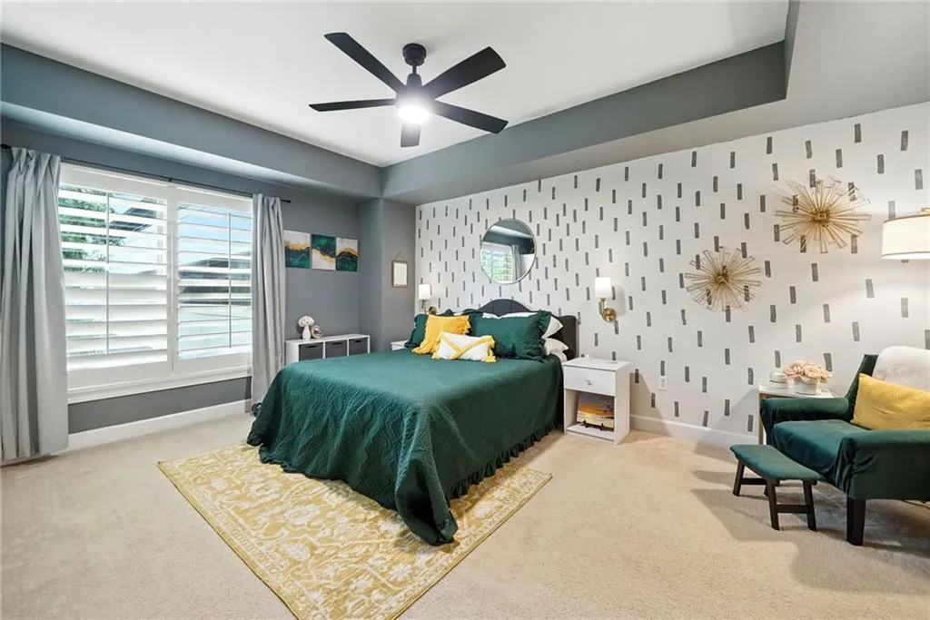 Bedroom featuring an accent wall, light colored carpet, and a ceiling fan