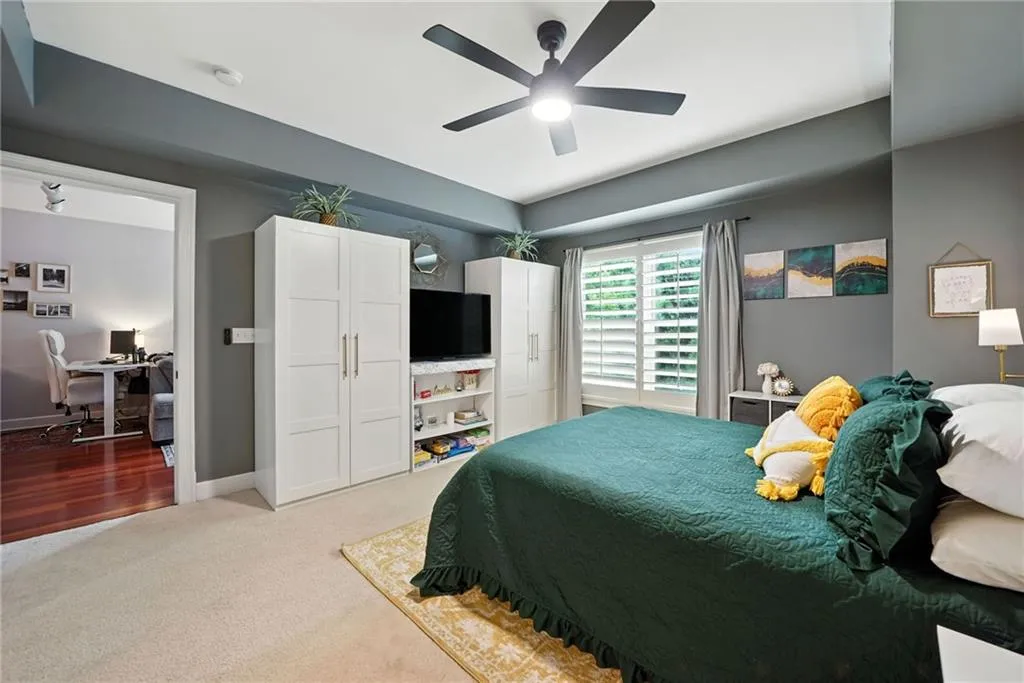 Bedroom with a desk, light colored carpet, and a ceiling fan
