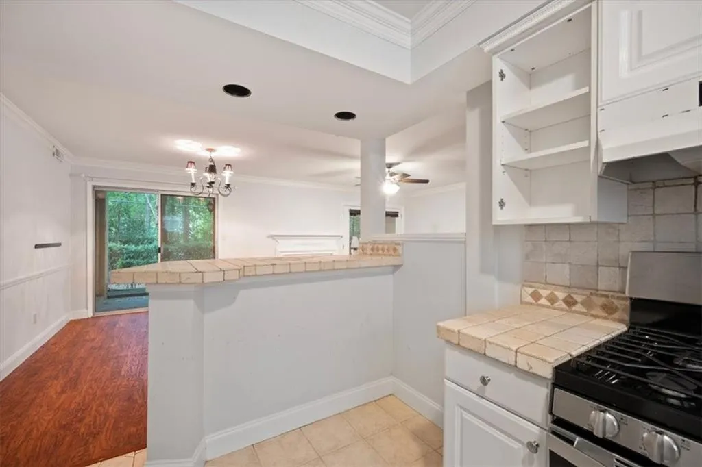 Kitchen featuring gas stove, open shelves, a peninsula, tasteful backsplash, and crown molding