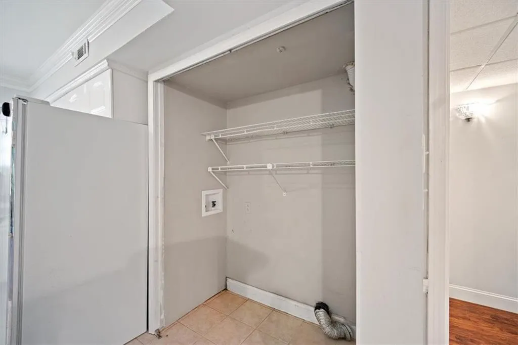 Washroom with hookup for a washing machine, crown molding, and light tile patterned floors