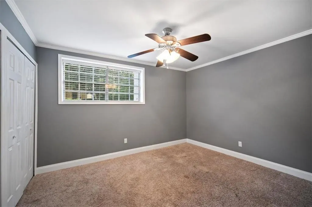 Unfurnished bedroom with carpet, ornamental molding, a closet, and ceiling fan