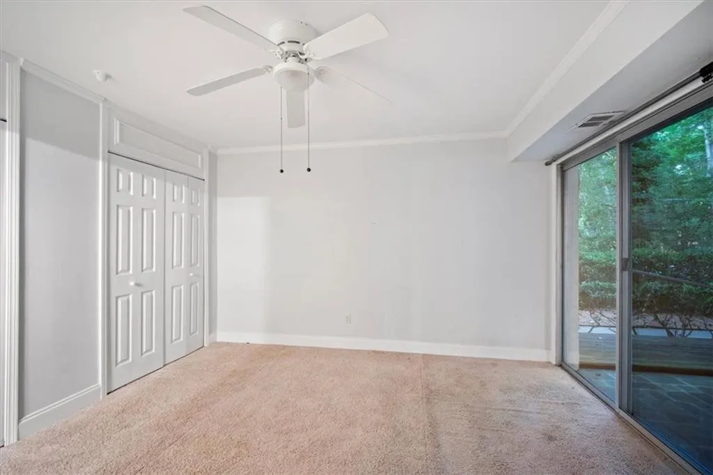 Unfurnished bedroom with access to exterior, carpet floors, crown molding, a ceiling fan, and a closet