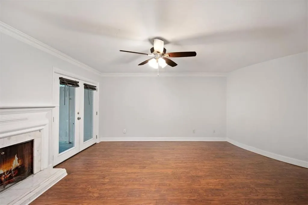 Unfurnished living room with a ceiling fan, a fireplace, wood finished floors, and ornamental molding