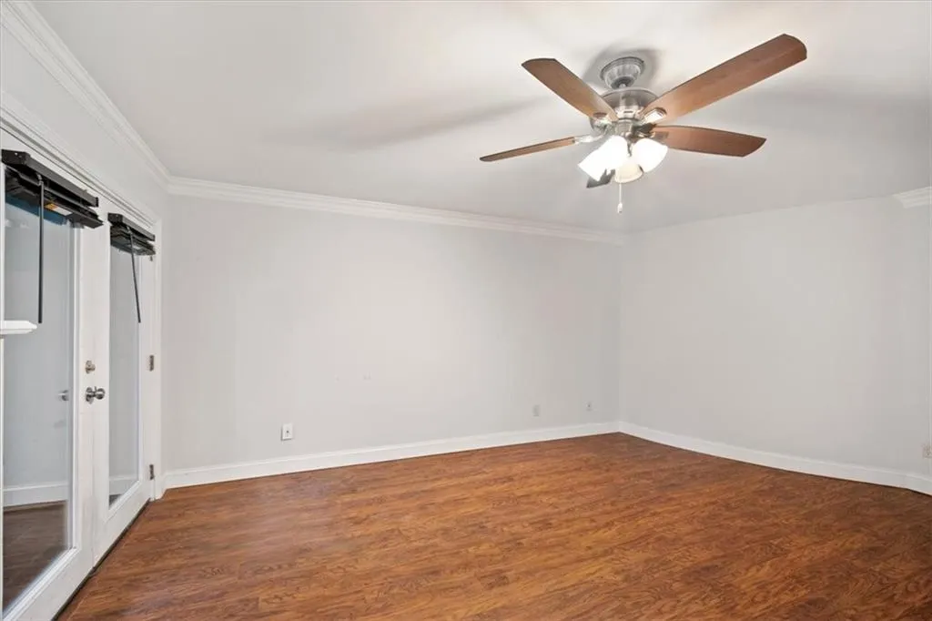 Spare room with ceiling fan, wood finished floors, and ornamental molding