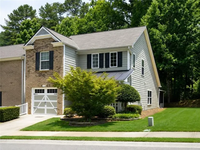 Two-story residence featuring a brick and siding exterior, a gable roofline, and a prominent front-facing garage with decorative windows