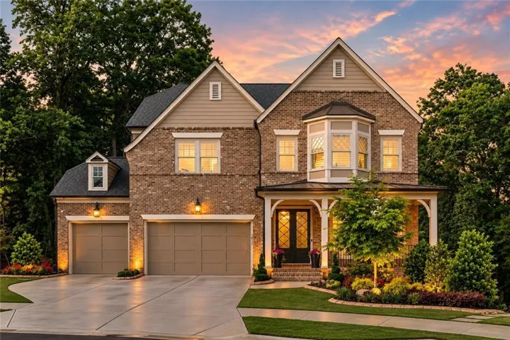 Brick and siding exterior featuring a covered front porch, two dormer windows, a bay window, and a two-car garage