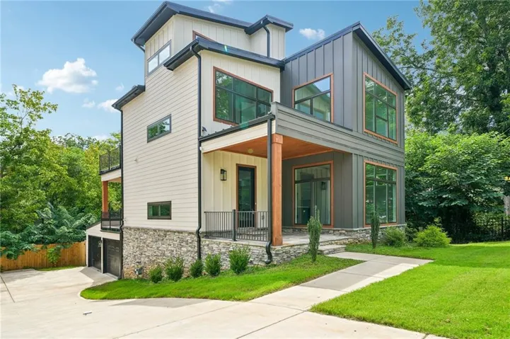 Modern exterior with mixed siding, stone accents, multiple balconies, a covered front entry, and a concrete driveway