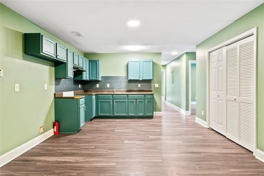 Kitchen featuring green cabinetry, tasteful backsplash, light wood-style flooring, under cabinet range hood, and recessed lighting