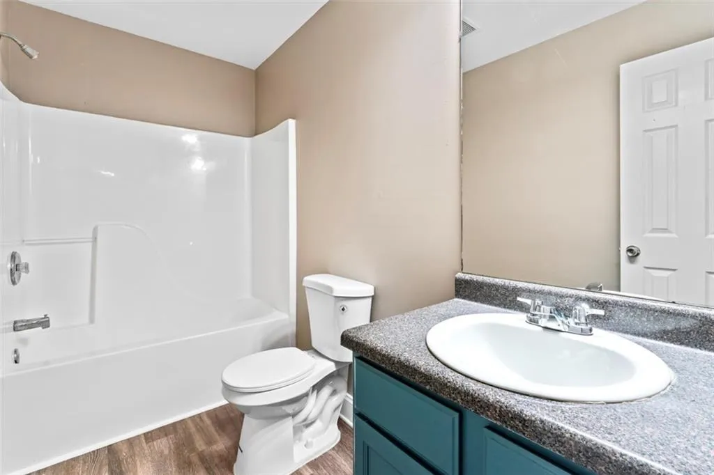 Bathroom featuring wood finished floors, vanity, and washtub / shower combination