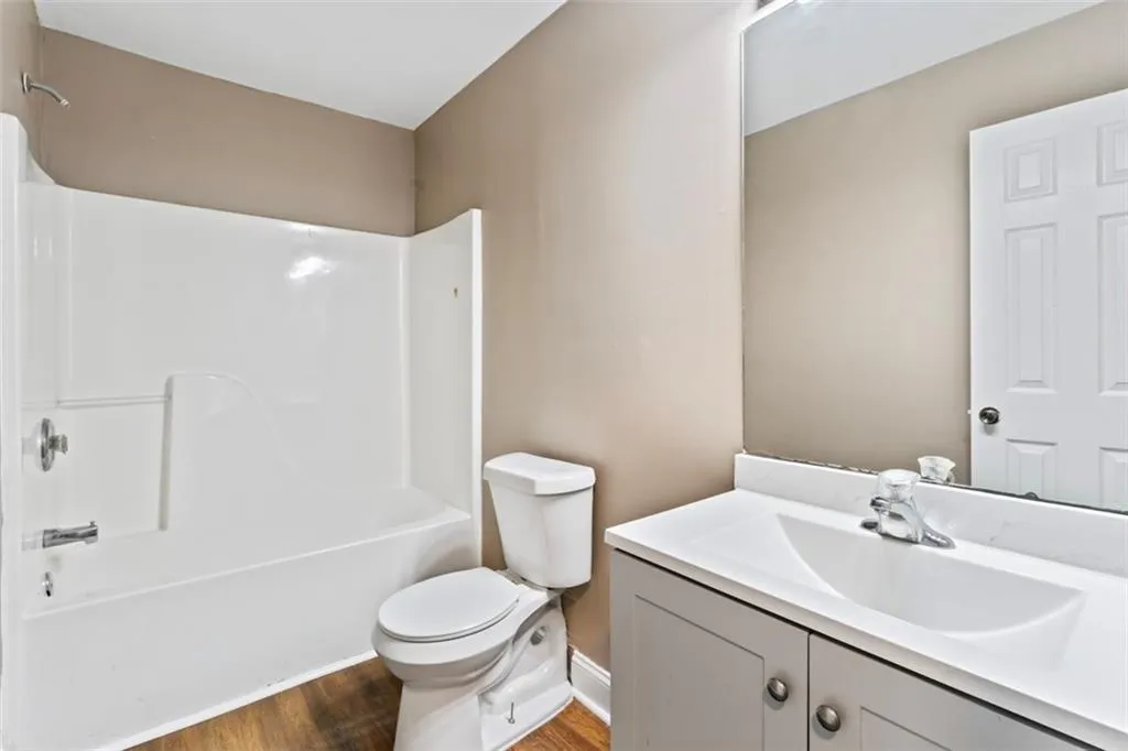 Bathroom with wood finished floors, vanity, and shower / tub combination
