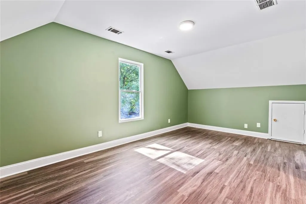 Additional living space with lofted ceiling and wood finished floors