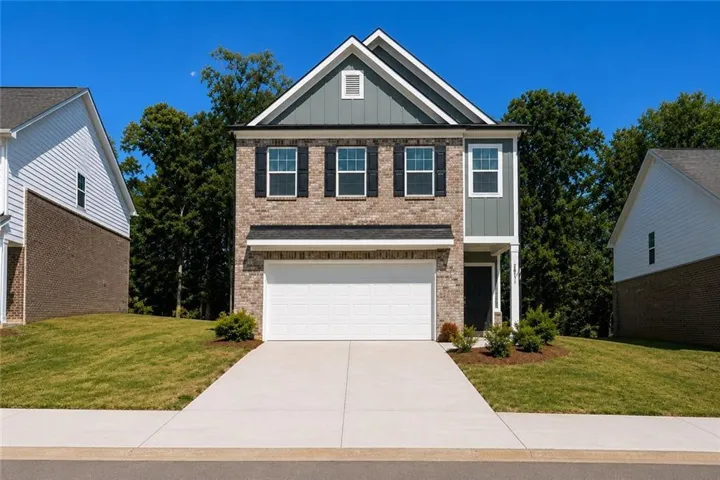 Brick and siding exterior featuring a prominent two-car garage, concrete driveway, and front entryway