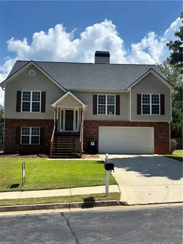Split-level residence featuring a brick and siding facade, an attached garage, and a concrete driveway