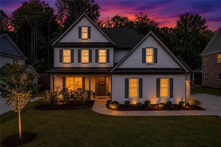 Two-story exterior with a covered front porch, dark-hued shutters, and dormer windows