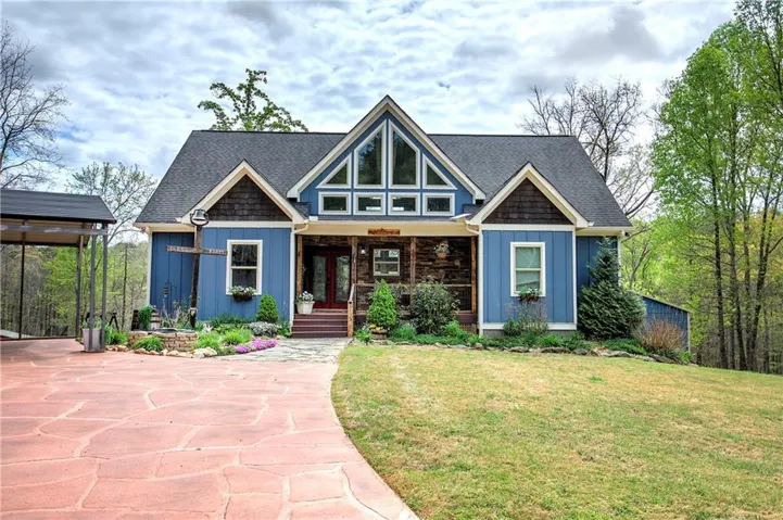 View of front facade featuring covered porch, a front lawn, and a shingled roof