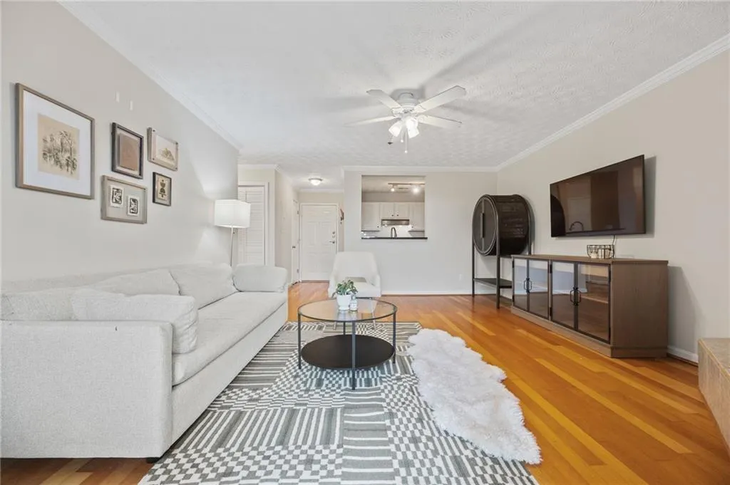 Living room featuring crown molding, a textured ceiling, ceiling fan, and wood finished floors
