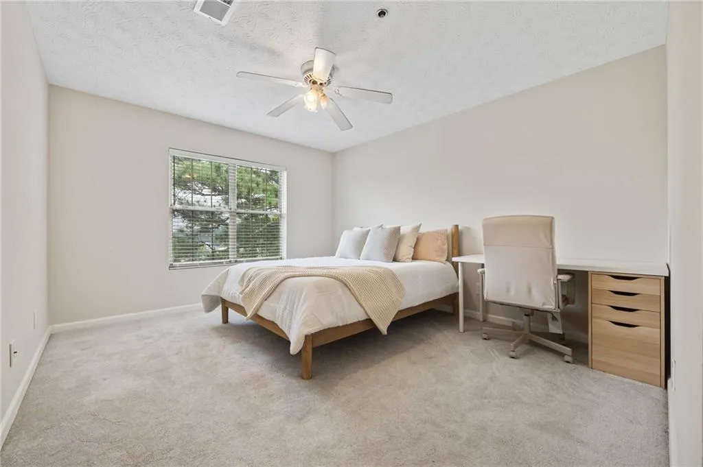 Bedroom featuring a textured ceiling, light colored carpet, visible vents, ceiling fan, and baseboards