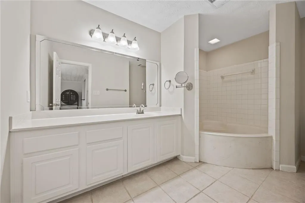 Bathroom with tile patterned floors, vanity, shower / tub combination, and baseboards