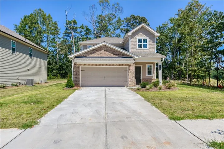 Modern Craftsman-style exterior featuring a two-car garage, brick facade, and shaker siding accents