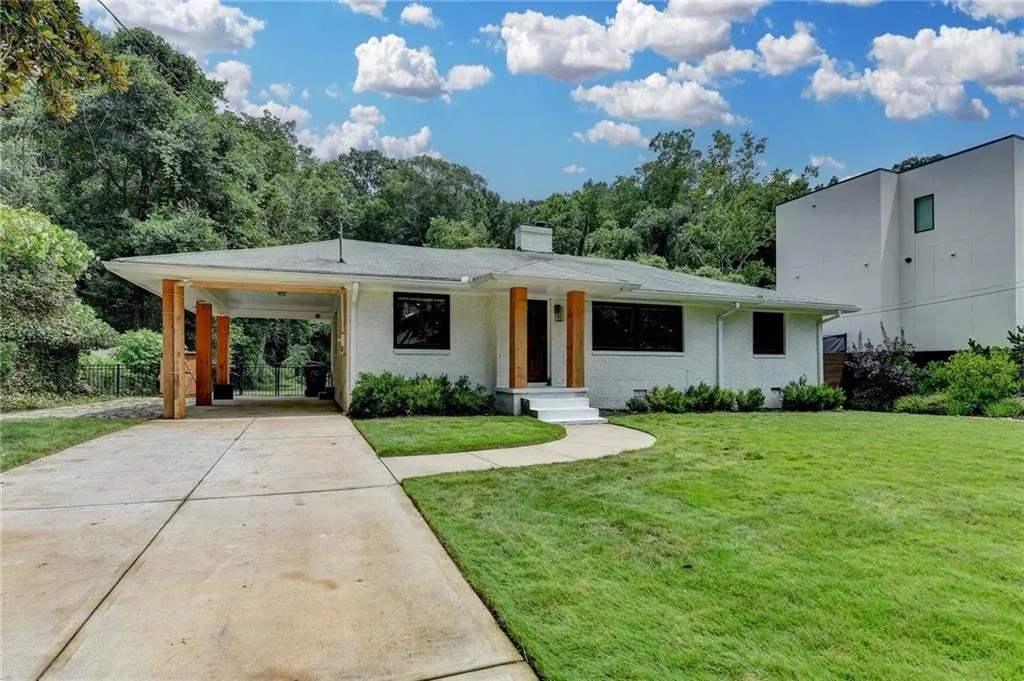 View of front of property with concrete driveway, a chimney, a carport, and brick siding