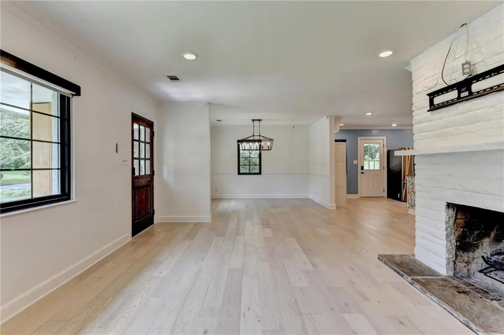 Foyer with light wood-type flooring, a chandelier, recessed lighting, a large fireplace, and crown molding