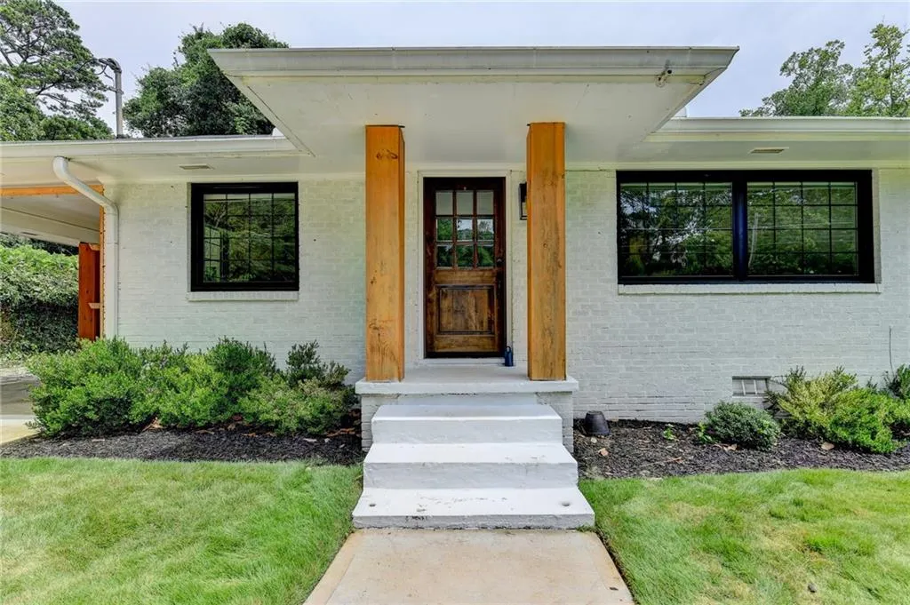 View of exterior entry with brick siding, a lawn, and crawl space