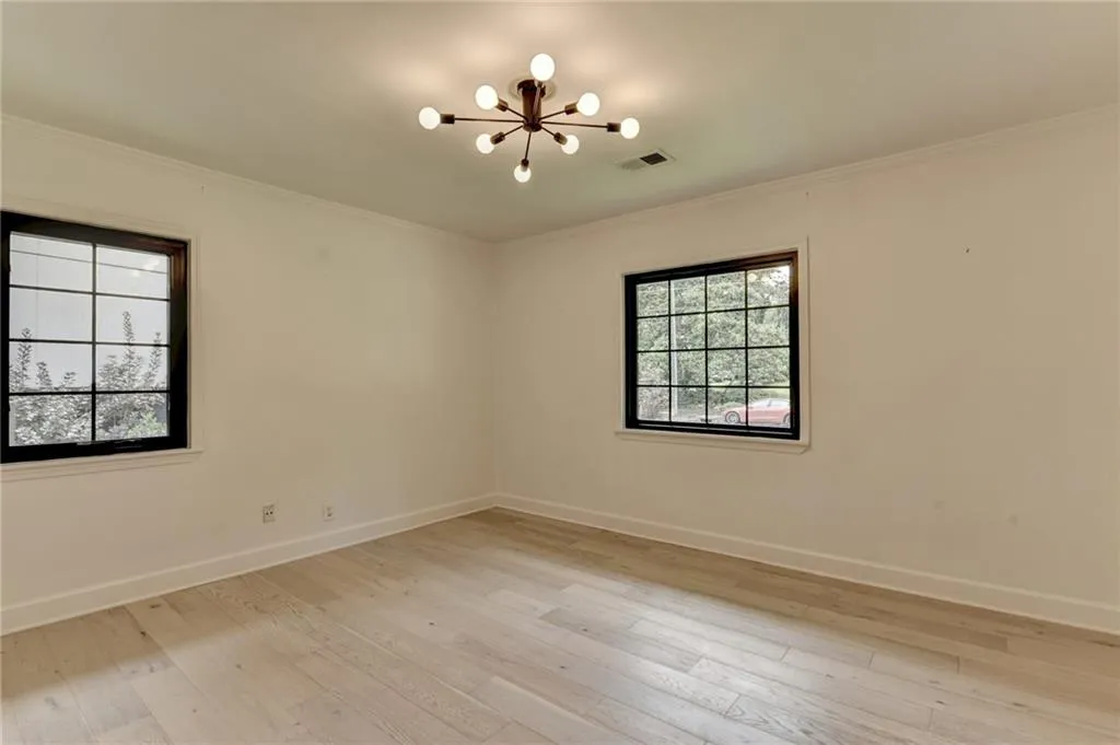Spare room with a chandelier, light wood-style floors, and crown molding