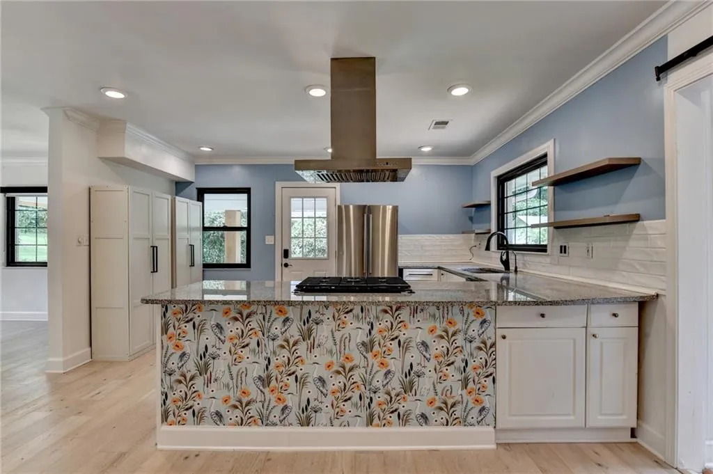 Kitchen featuring island exhaust hood, freestanding refrigerator, stone countertops, gas cooktop, and plenty of natural light