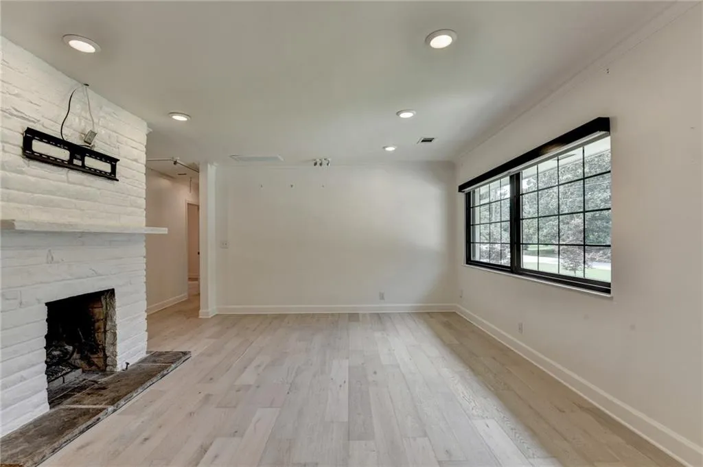 Unfurnished living room with a large fireplace, light wood-style floors, and recessed lighting