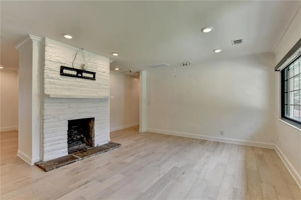 Unfurnished living room featuring light wood-type flooring, a stone fireplace, recessed lighting, and crown molding