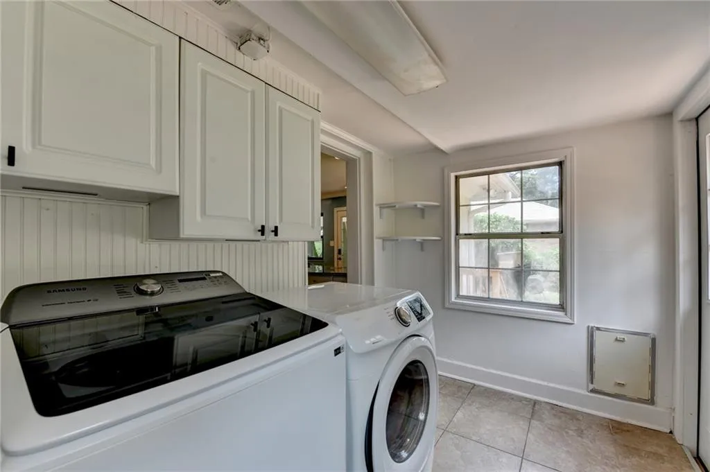 Washroom featuring cabinet space, washing machine and clothes dryer, and light tile patterned floors