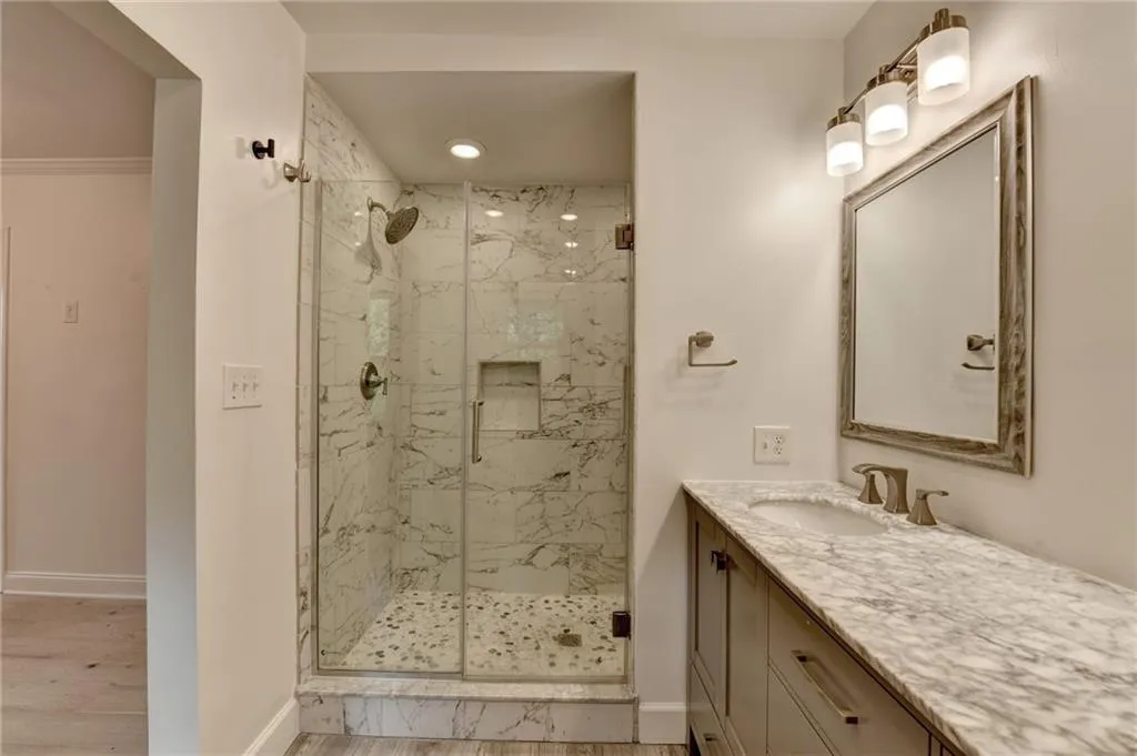 Full bath with a marble finish shower, vanity, wood finished floors, and recessed lighting