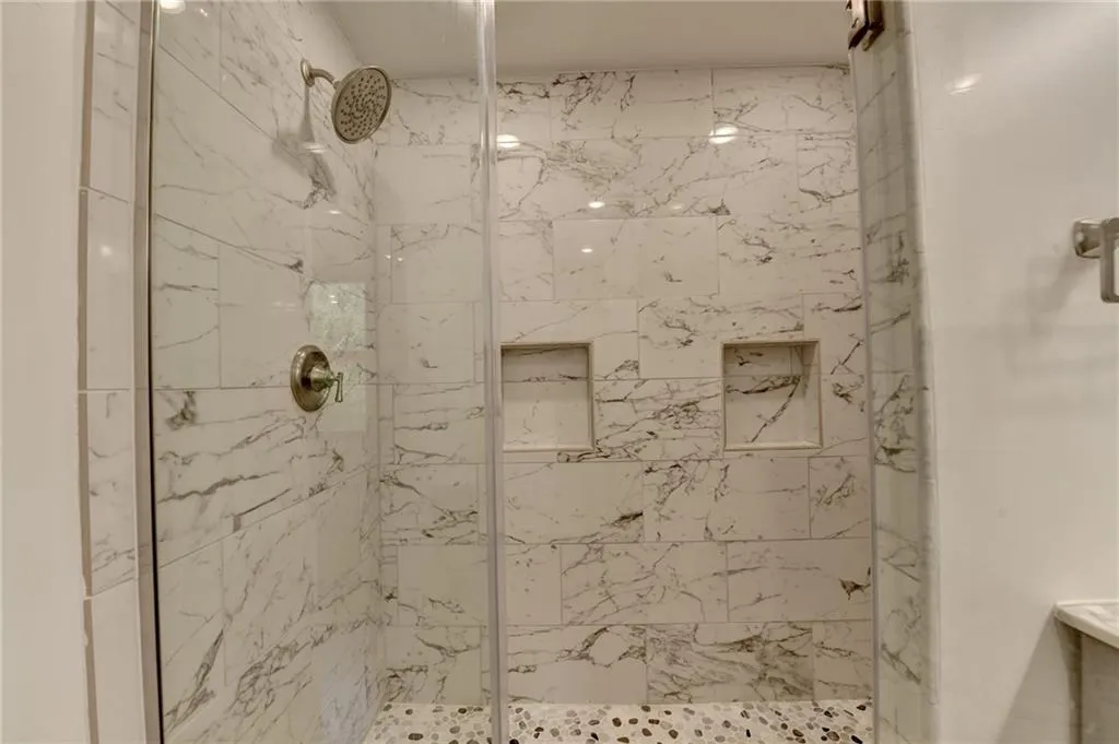 Full bath with a marble finish shower