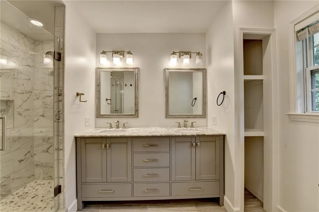 Bathroom featuring a marble finish shower and double vanity