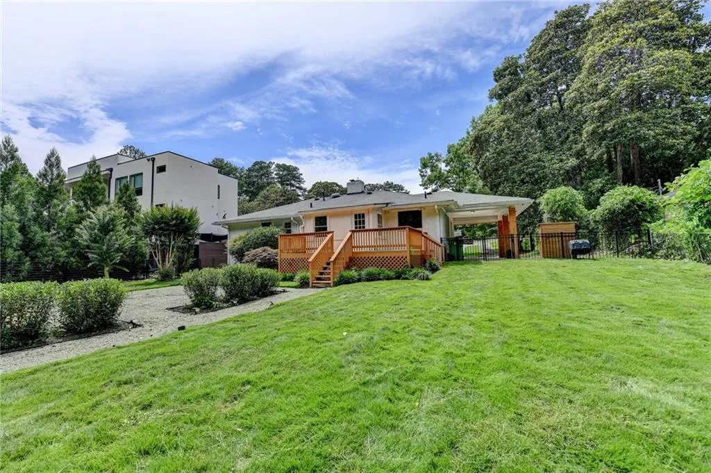 View of front of property featuring a fenced backyard, a deck, a gate, a chimney, and stairway