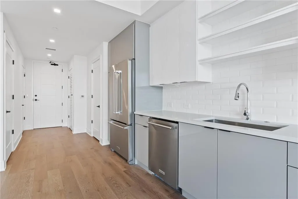 Kitchen featuring open shelves, modern cabinets, stainless steel appliances, light countertops, and recessed lighting