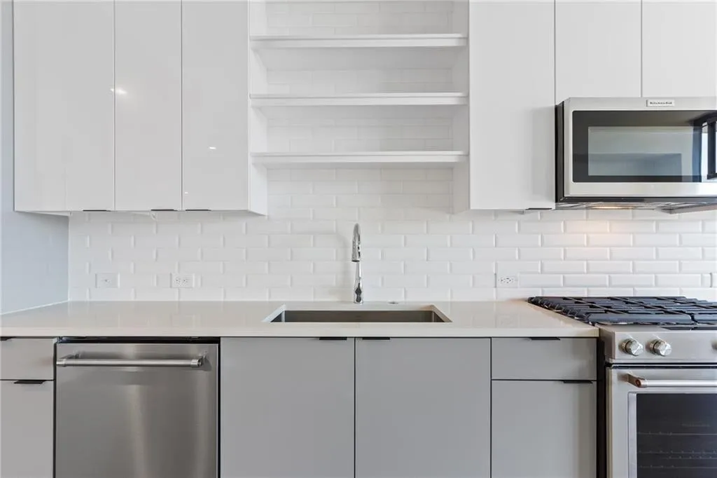 Kitchen featuring modern cabinets, appliances with stainless steel finishes, white cabinets, and light countertops