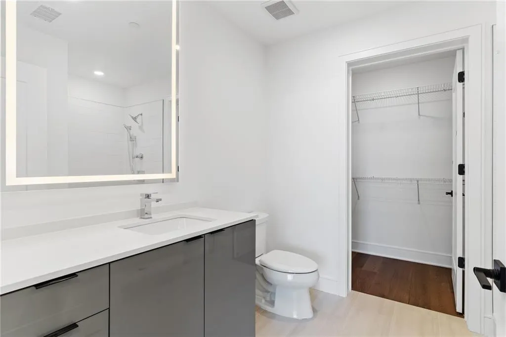 Full bath with vanity, tiled shower, a spacious closet, wood finished floors, and recessed lighting