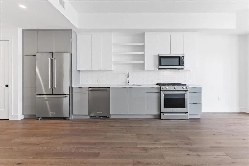 Kitchen with gray cabinets, open shelves, premium appliances, modern cabinets, and tasteful backsplash