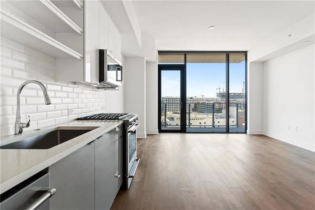 Kitchen with stainless steel appliances, tasteful backsplash, modern cabinets, dark wood-style floors, and light stone counters