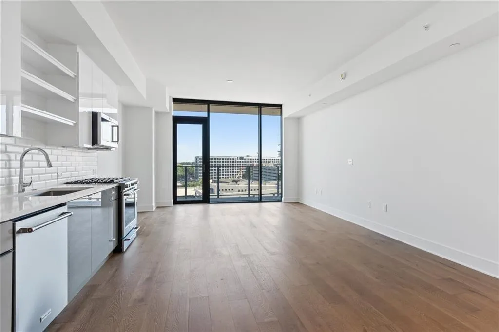 Kitchen featuring modern cabinets, appliances with stainless steel finishes, decorative backsplash, dark wood-style flooring, and light countertops