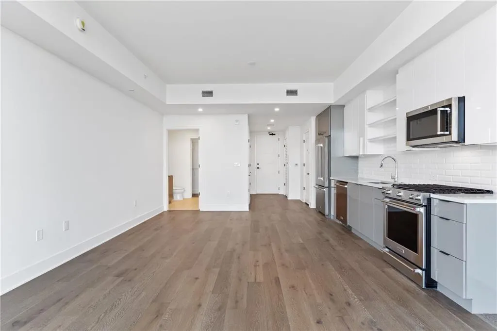 Kitchen with open shelves, high quality appliances, modern cabinets, light countertops, and light wood-style flooring